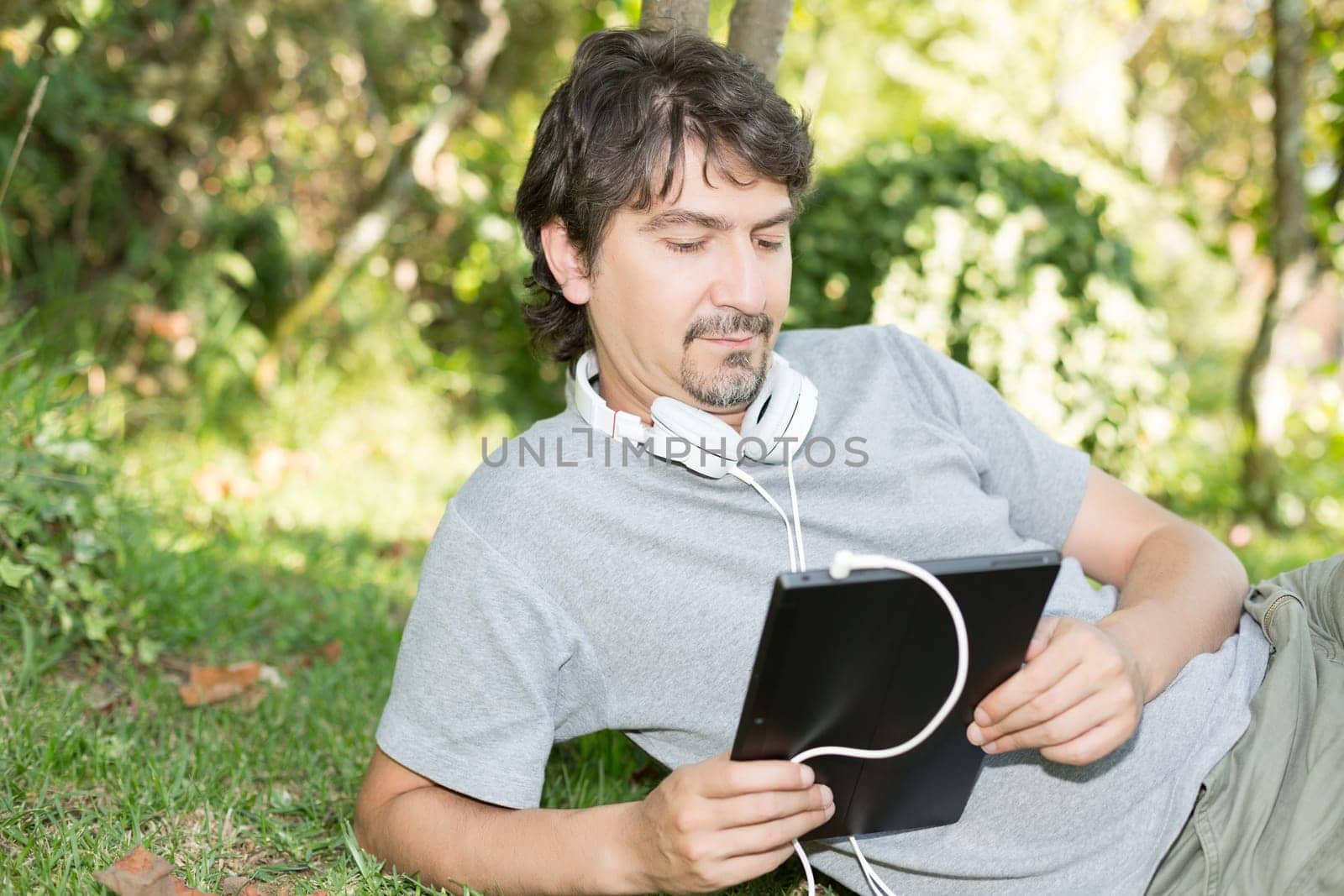 Young man relaxing with a tablet computer at a garden