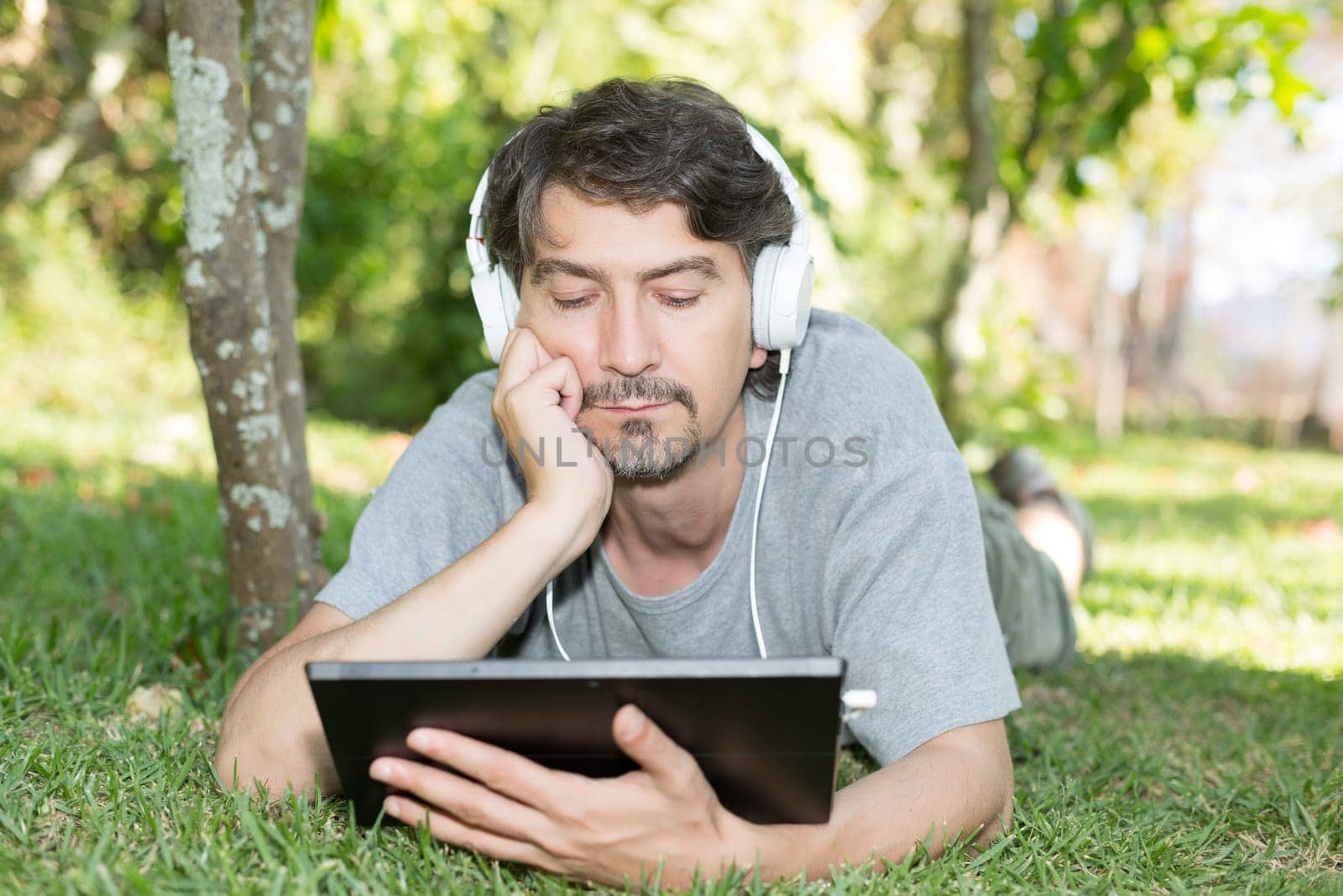 Young man relaxing with a tablet computer at a garden