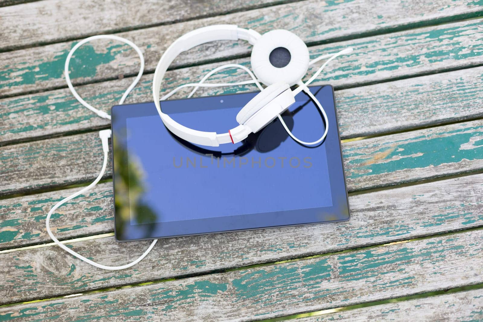 Tablet computer with headphones against wooden background
