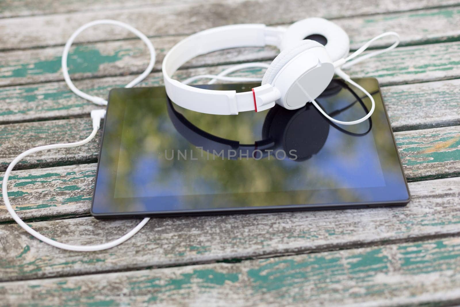 Tablet computer with headphones against wooden background