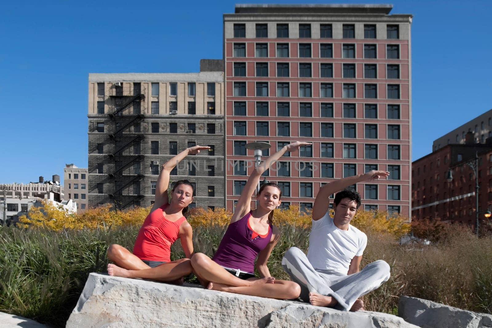 Man exercising with two women on a rock