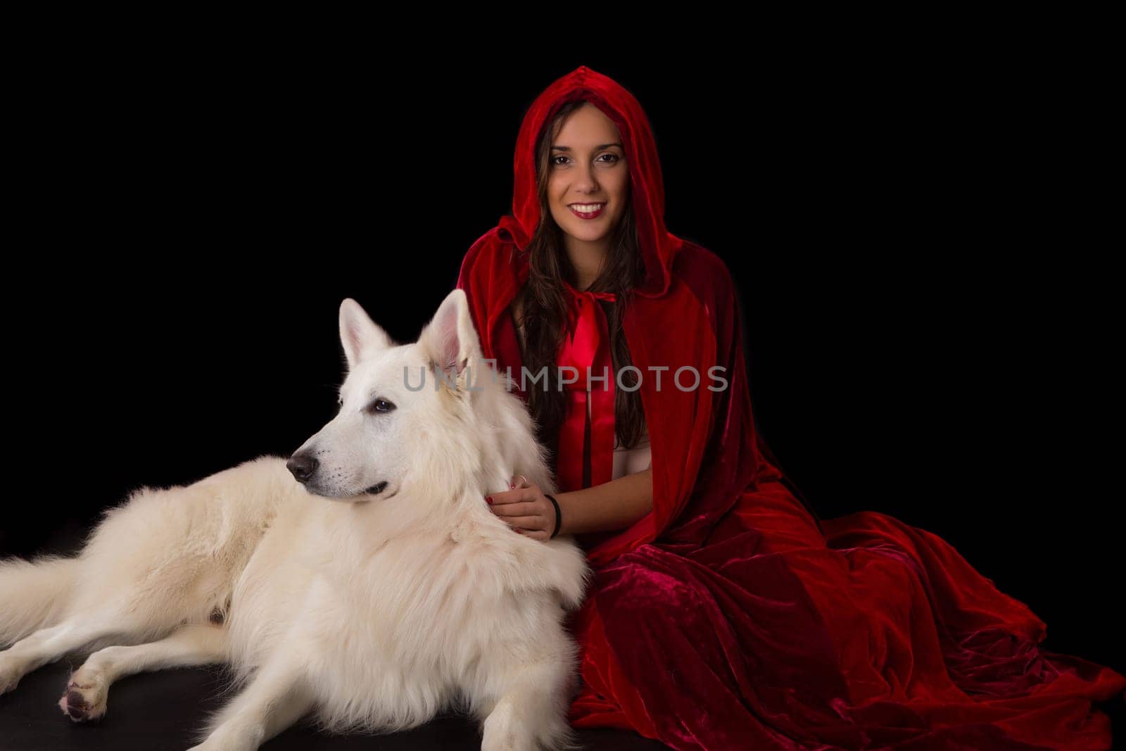 Woman wearing a red hood posing in studio with her dog