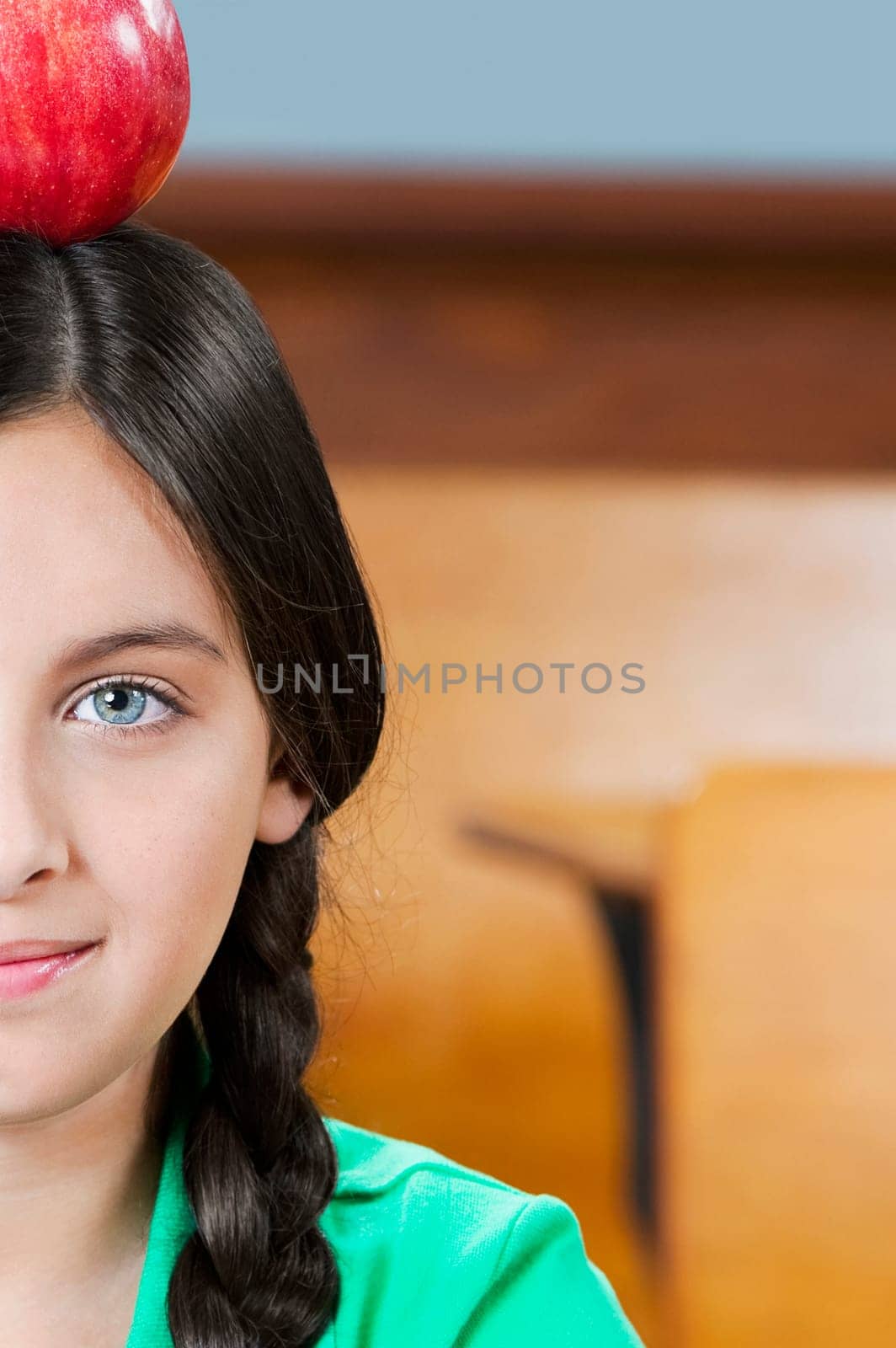 Schoolgirl carrying an apple on her head in a classroom