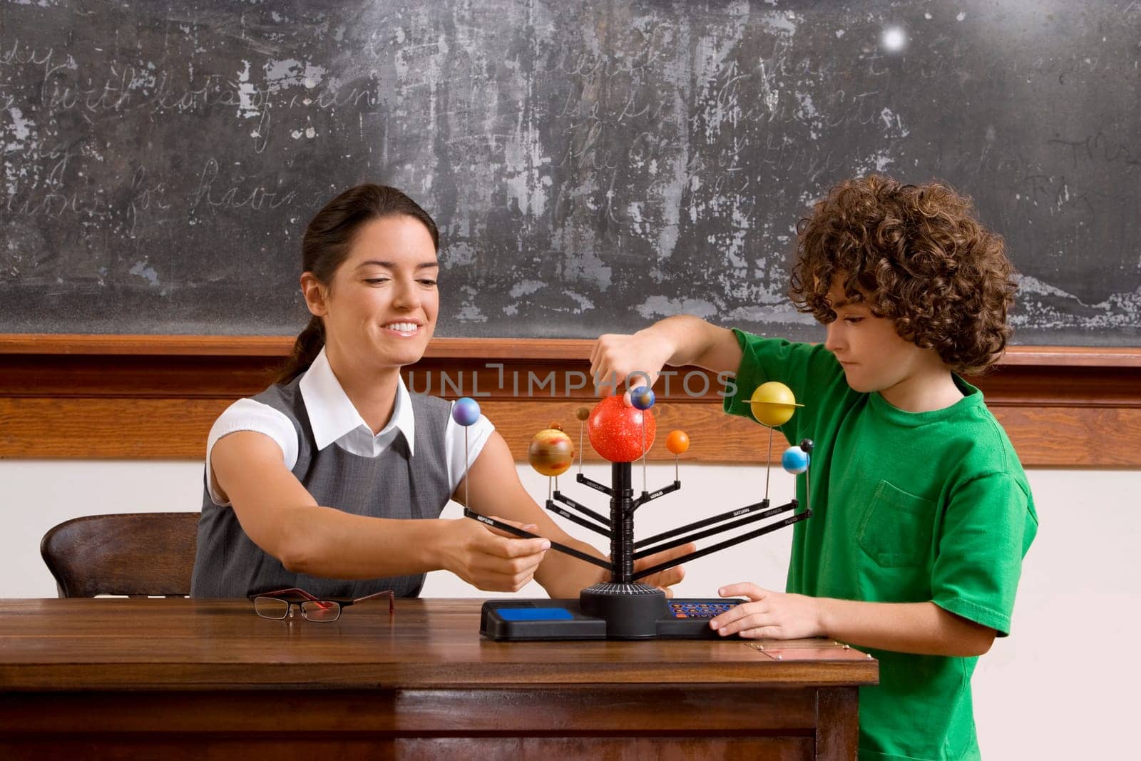 Schoolboy and his teacher with model of solar system in a classroom