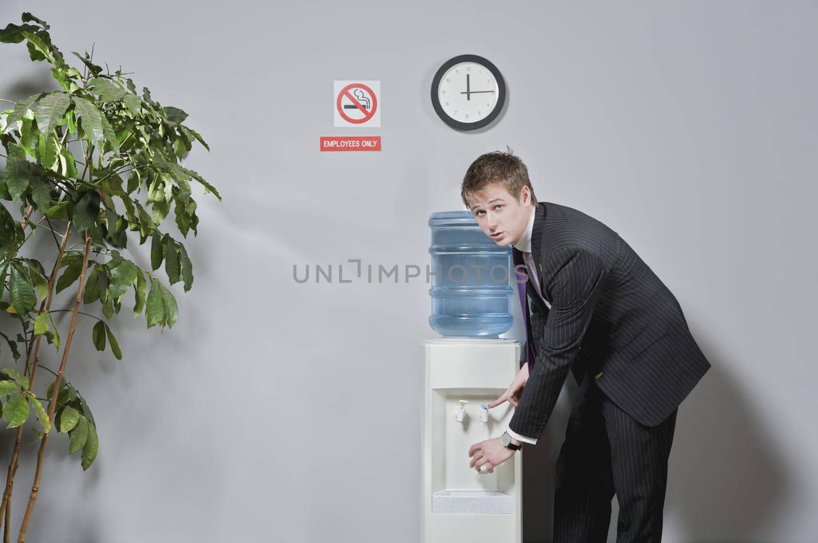 Portrait of a businessman pouring water into a glass from a water cooler