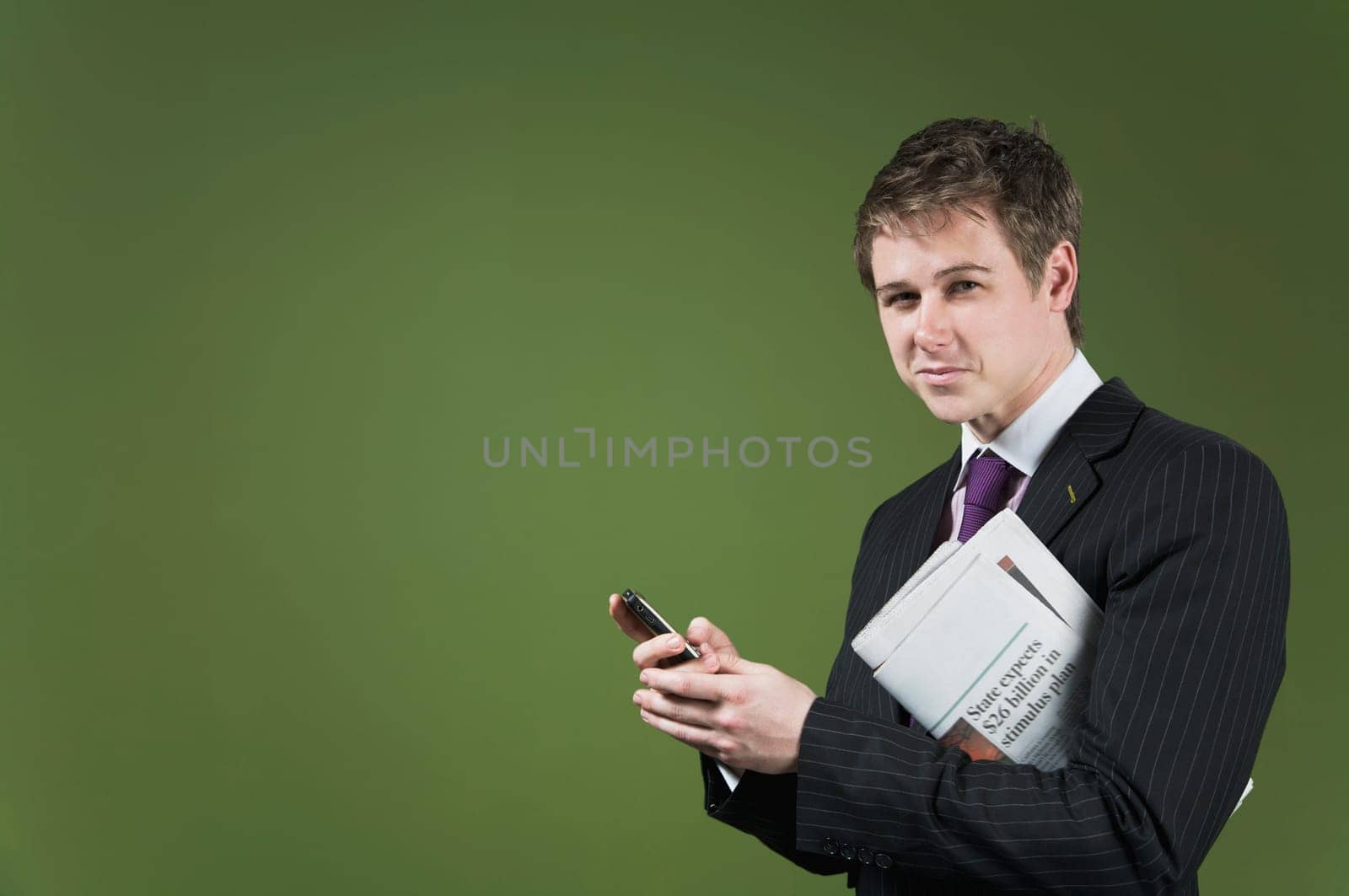 Portrait of a businessman holding a mobile phone and a newspaper