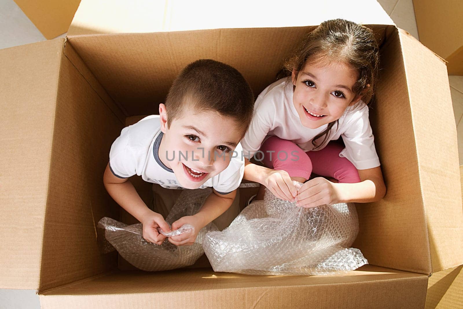 Portrait of two children sitting in a cardboard box and smiling