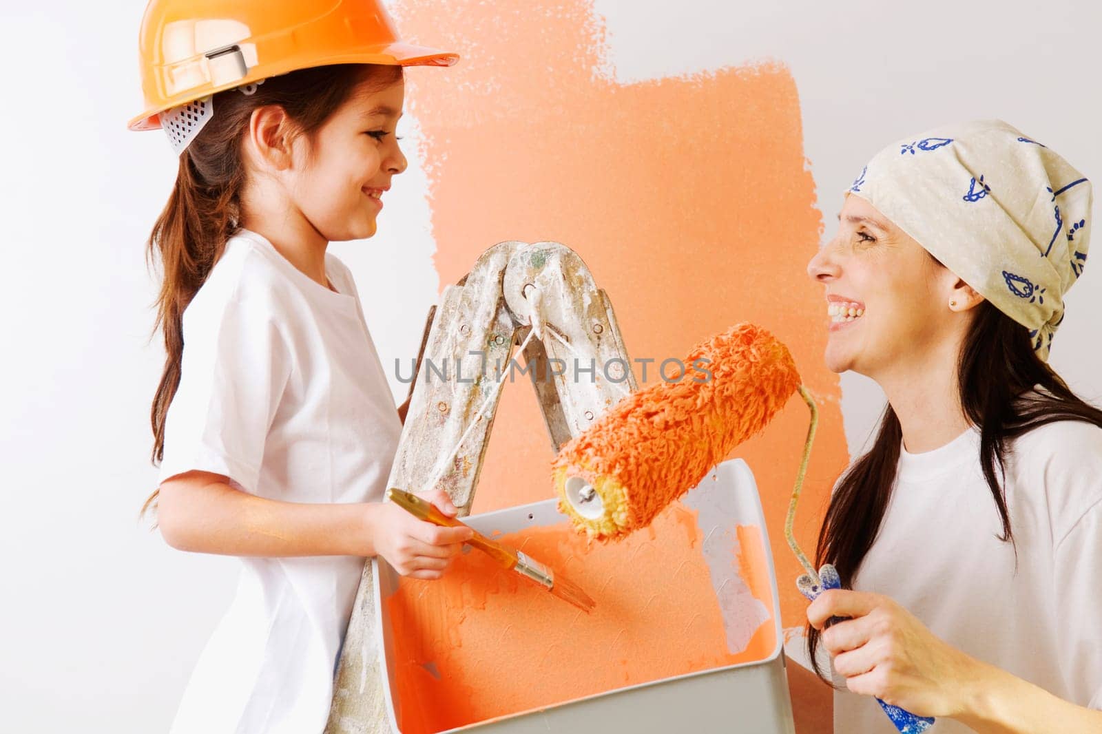 Close_up of a mature woman and her daughter painting a wall