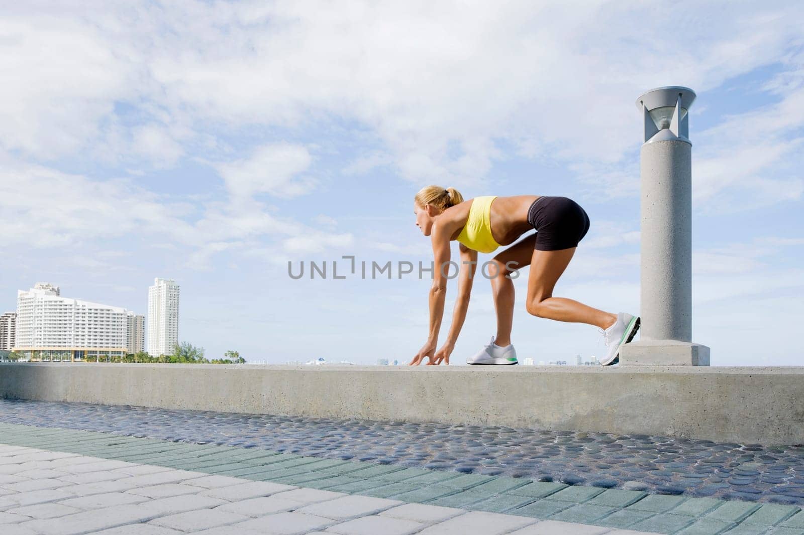 Side profile of a mid adult woman in a running position on the ledge