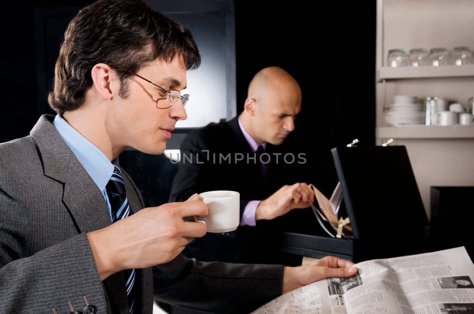 Businessman holding a cup of tea and reading a newspaper