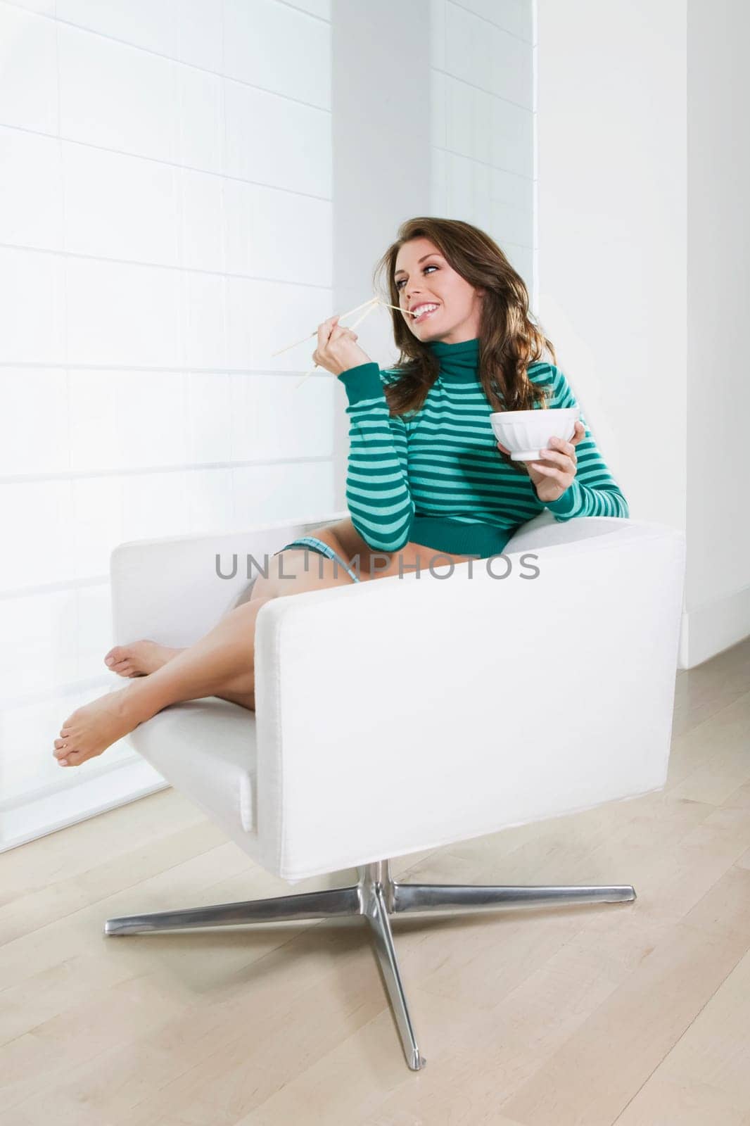 Young woman sitting in an armchair and eating food