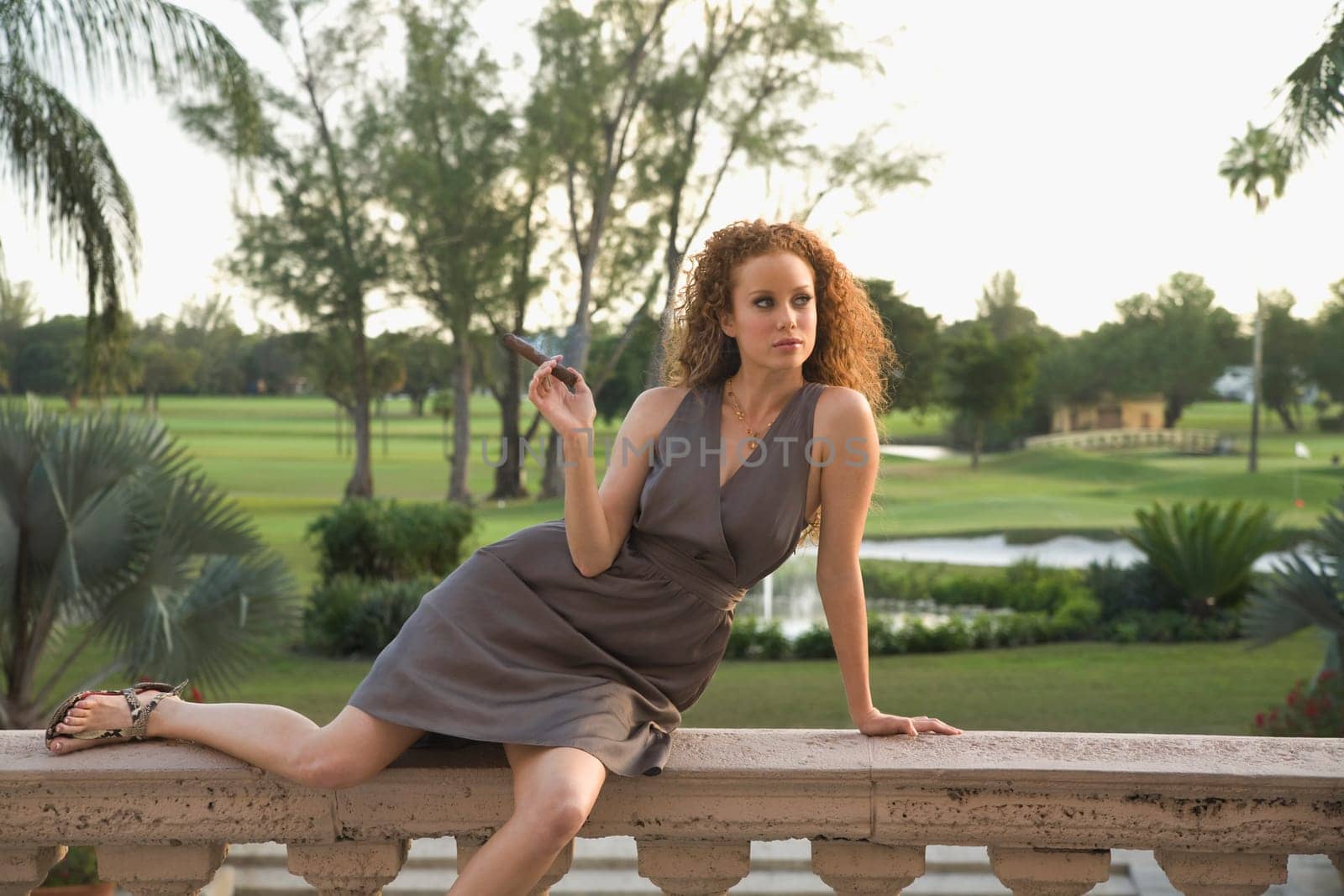 Woman sitting on balustrade and smoking a cigar, Biltmore Hotel, Coral Gables, Florida, USA