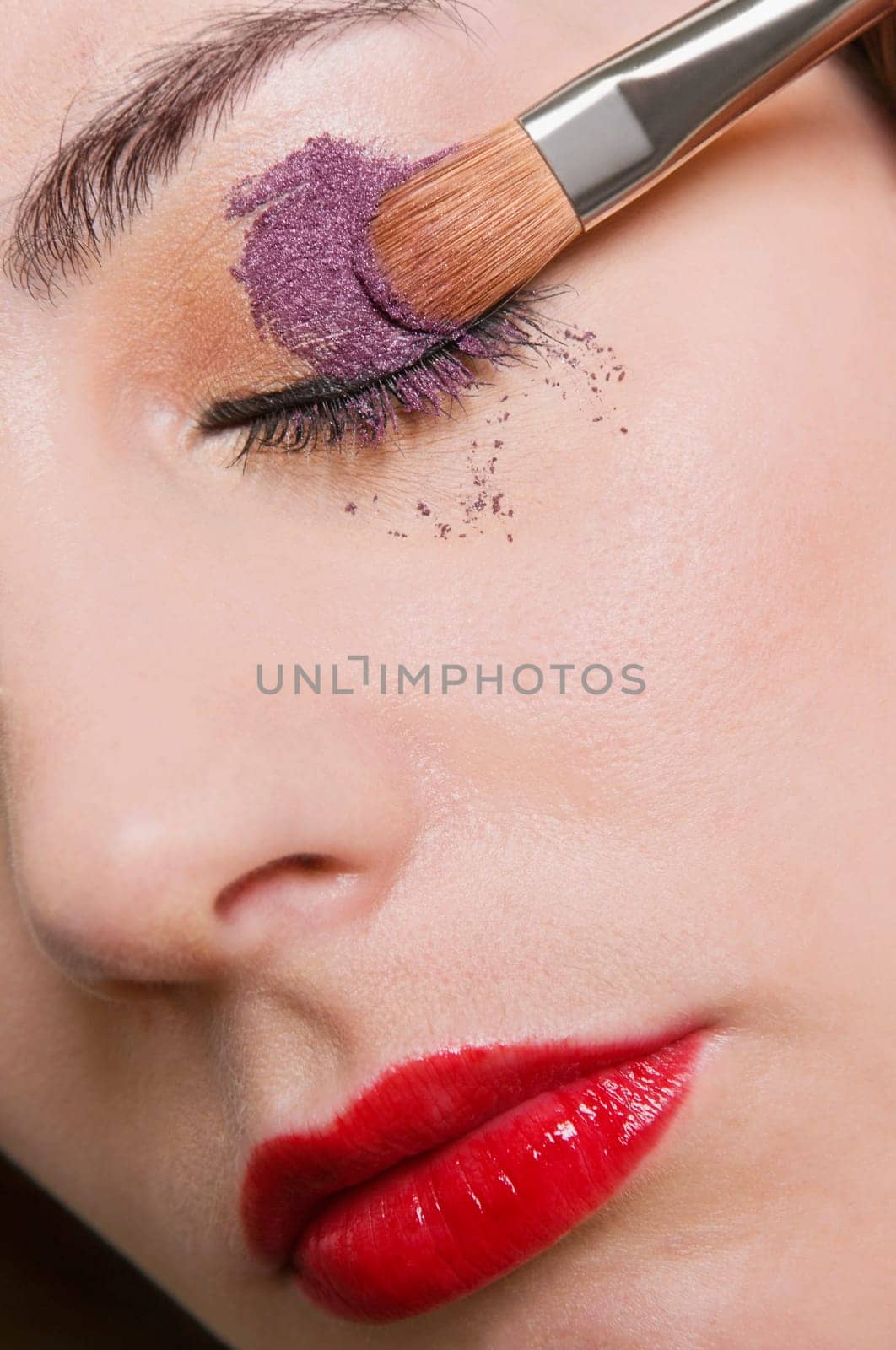 Close_up of a young woman applying eyeshadow