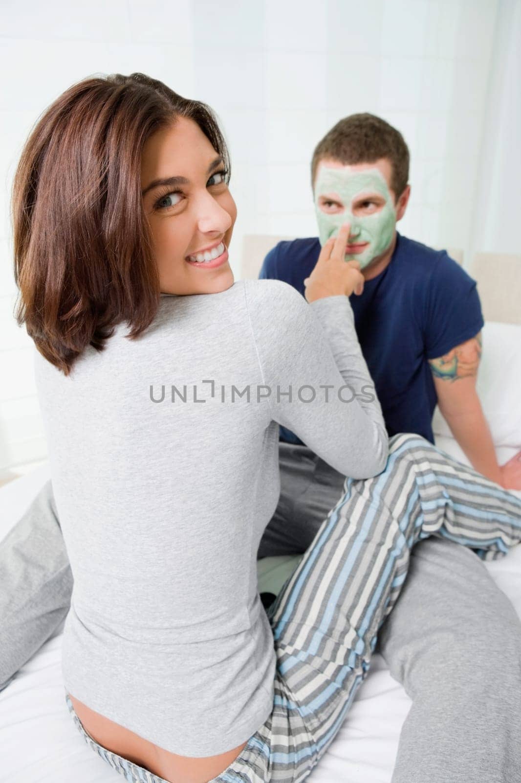 Portrait of a young woman applying facial mask on a young manŽs face