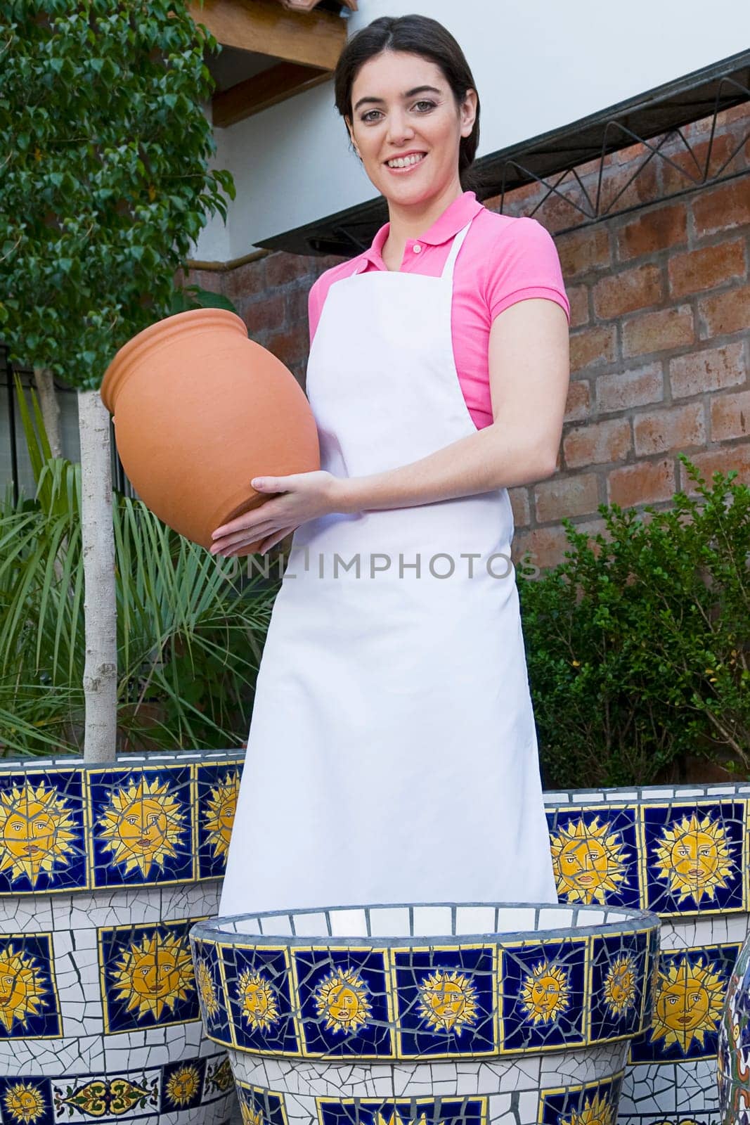 Woman holding a decorative urn in a greenhouse