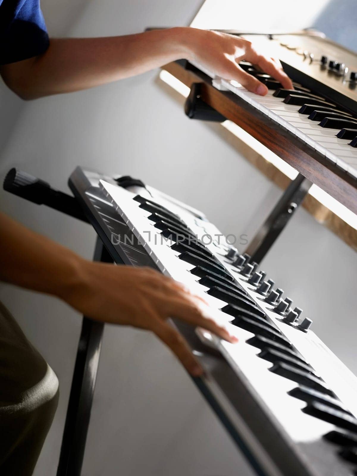 Close-up of a person's hands playing two electric pianos