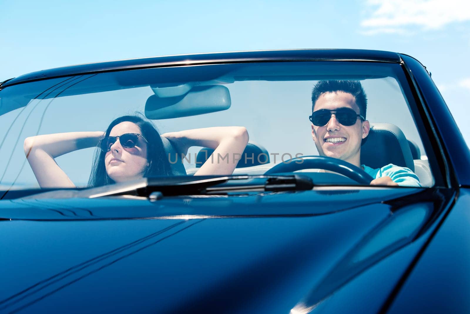 Portrait of attractive young teen Couple driving convertible.