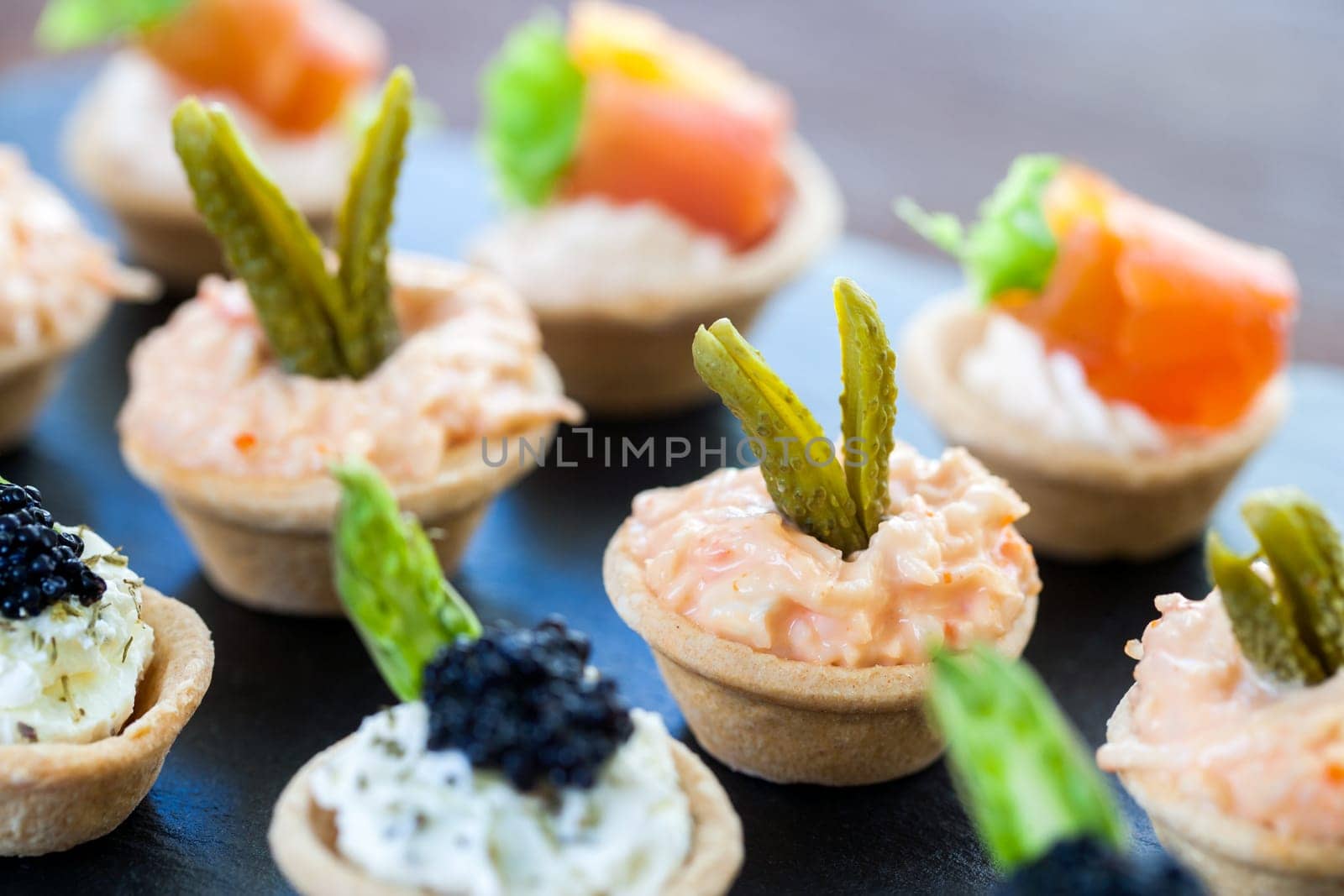 Macro close up of Multiple mini pastry tartlets with variety of seafood filling.