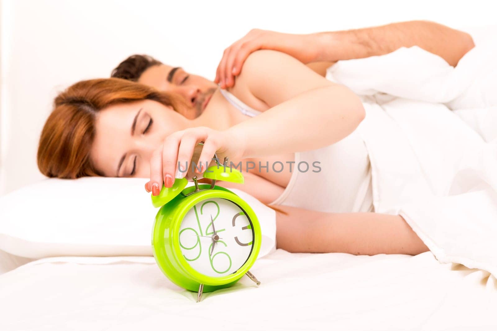Couple is sleeping and the alarm clock starts to ring - time to wake up!