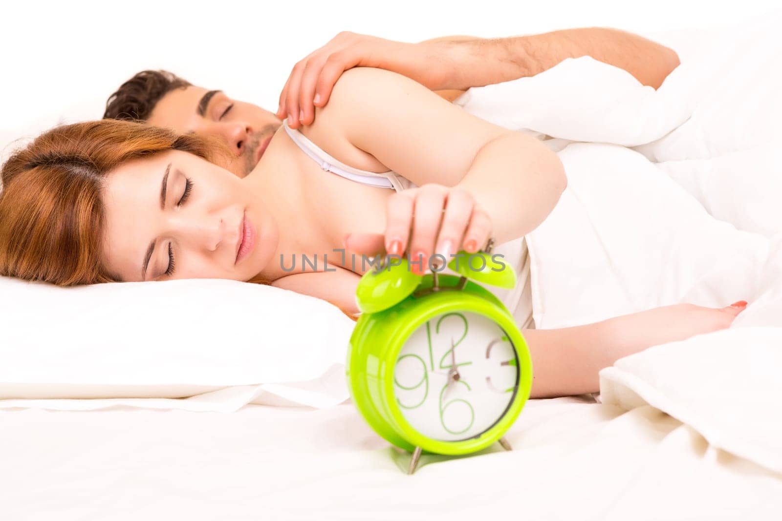 Couple is sleeping and the alarm clock starts to ring - time to wake up!
