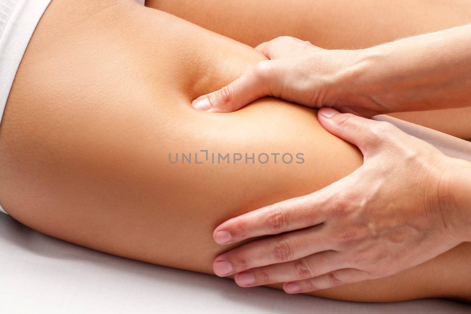 Macro close up of Physiotherapist hands massaging hamstring on female athlete.