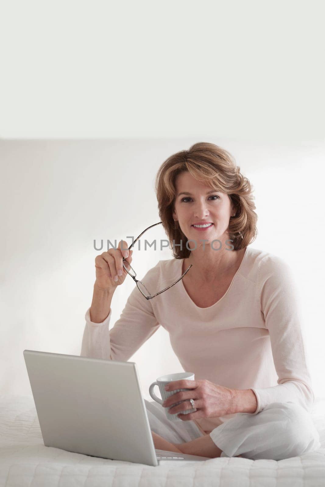 Woman working on a laptop and holding a cup of coffee