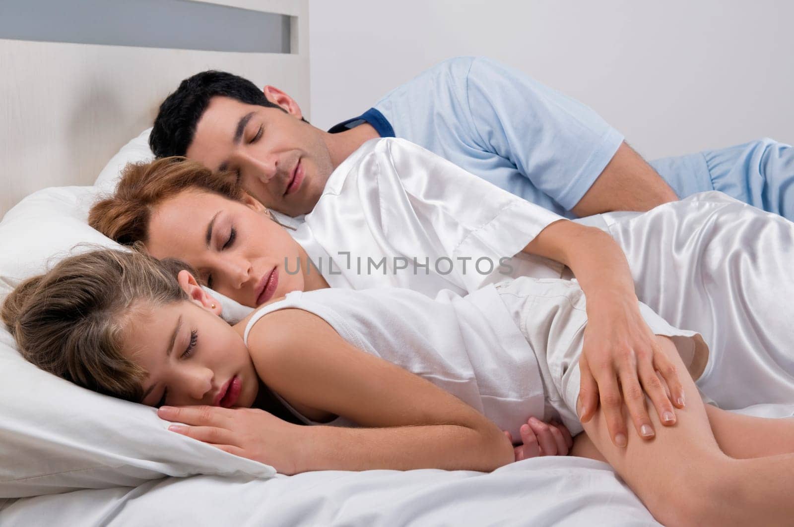 Mid adult couple sleeping with their daughter