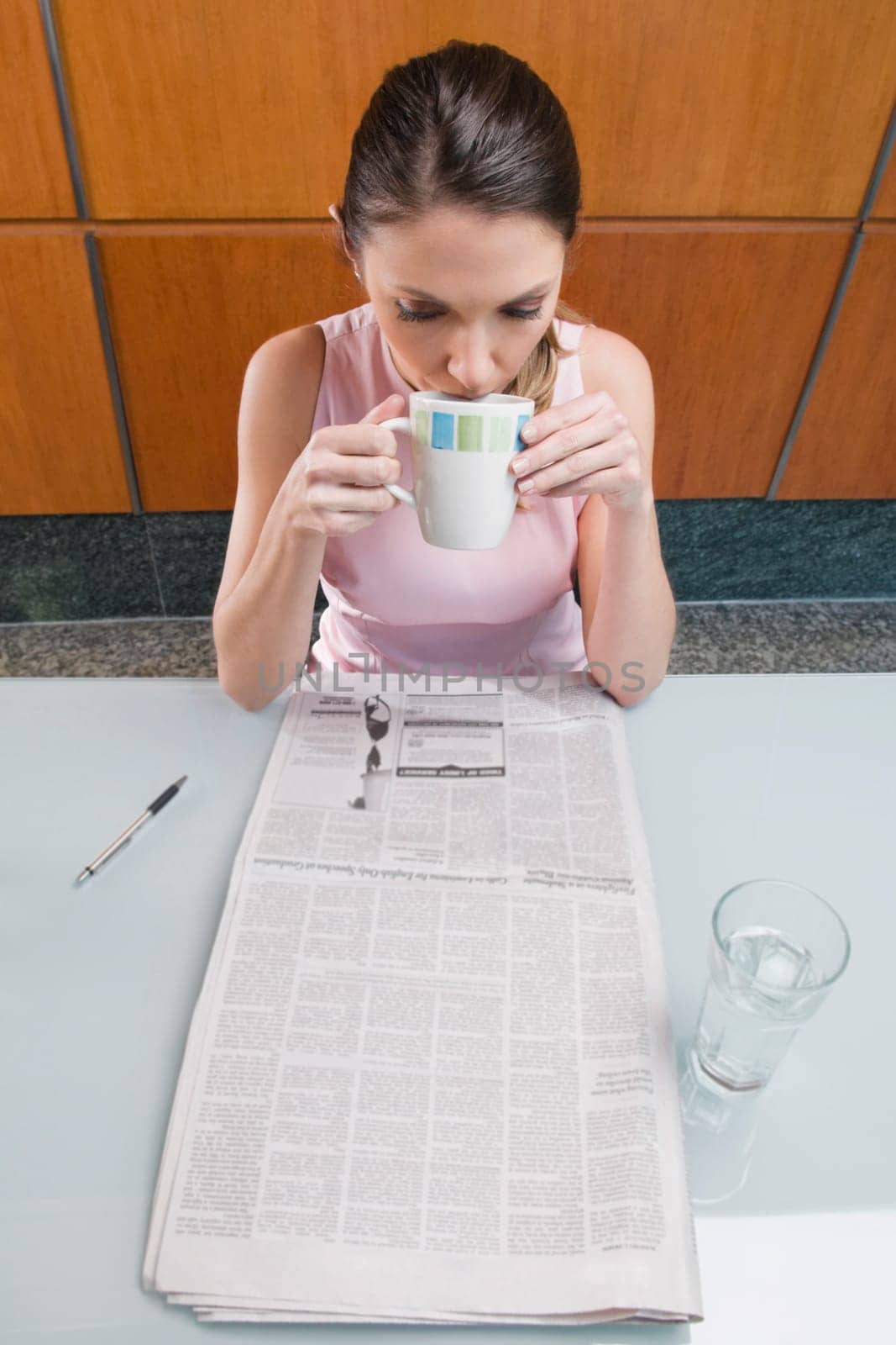 High angle view of a businesswoman drinking coffee and reading a newspaper