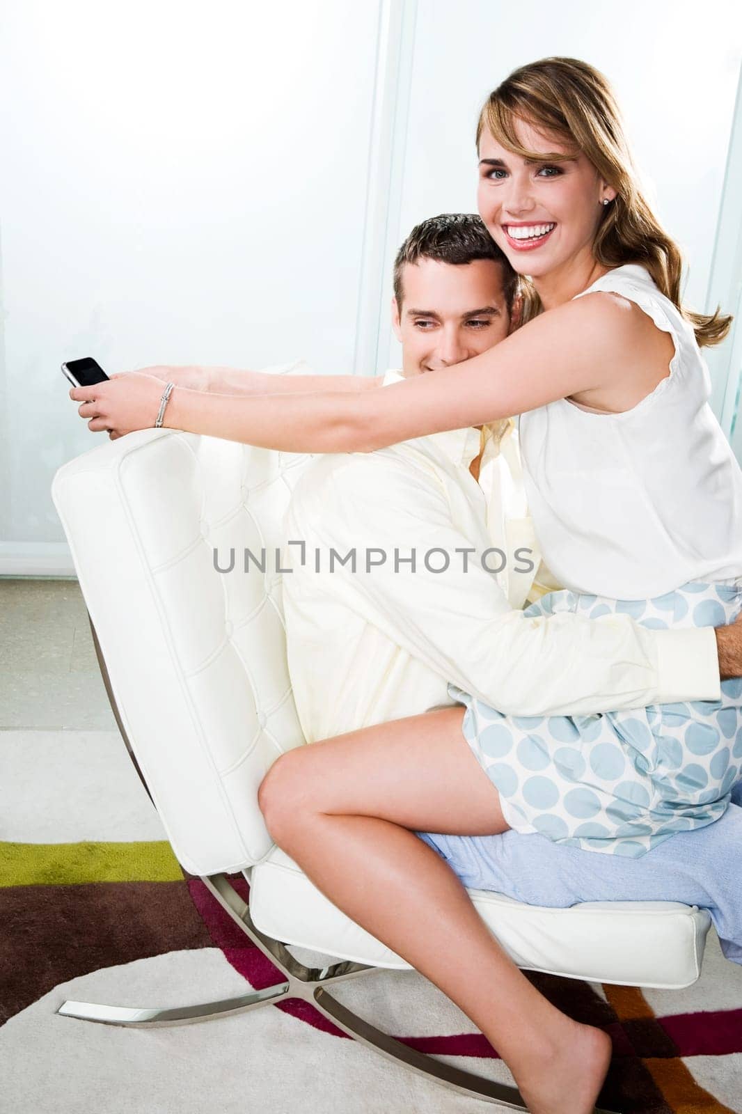Portrait of a young woman sitting on the lap of a young man and smiling