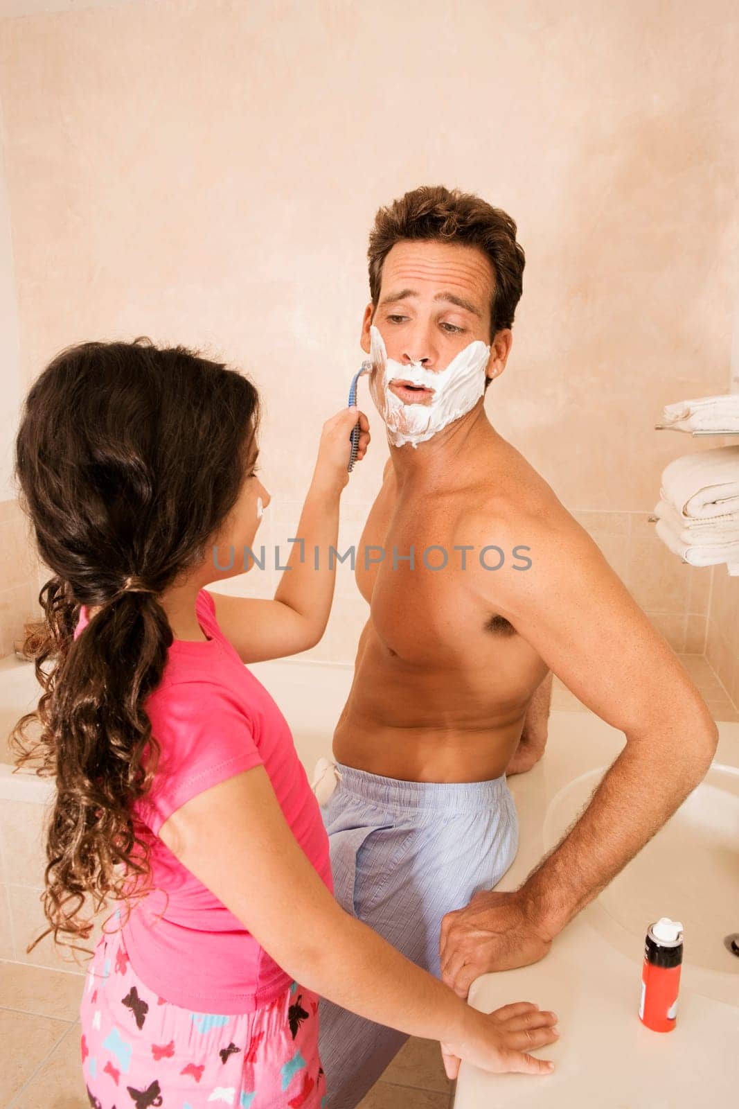 Girl shaving her father in the bathroom
