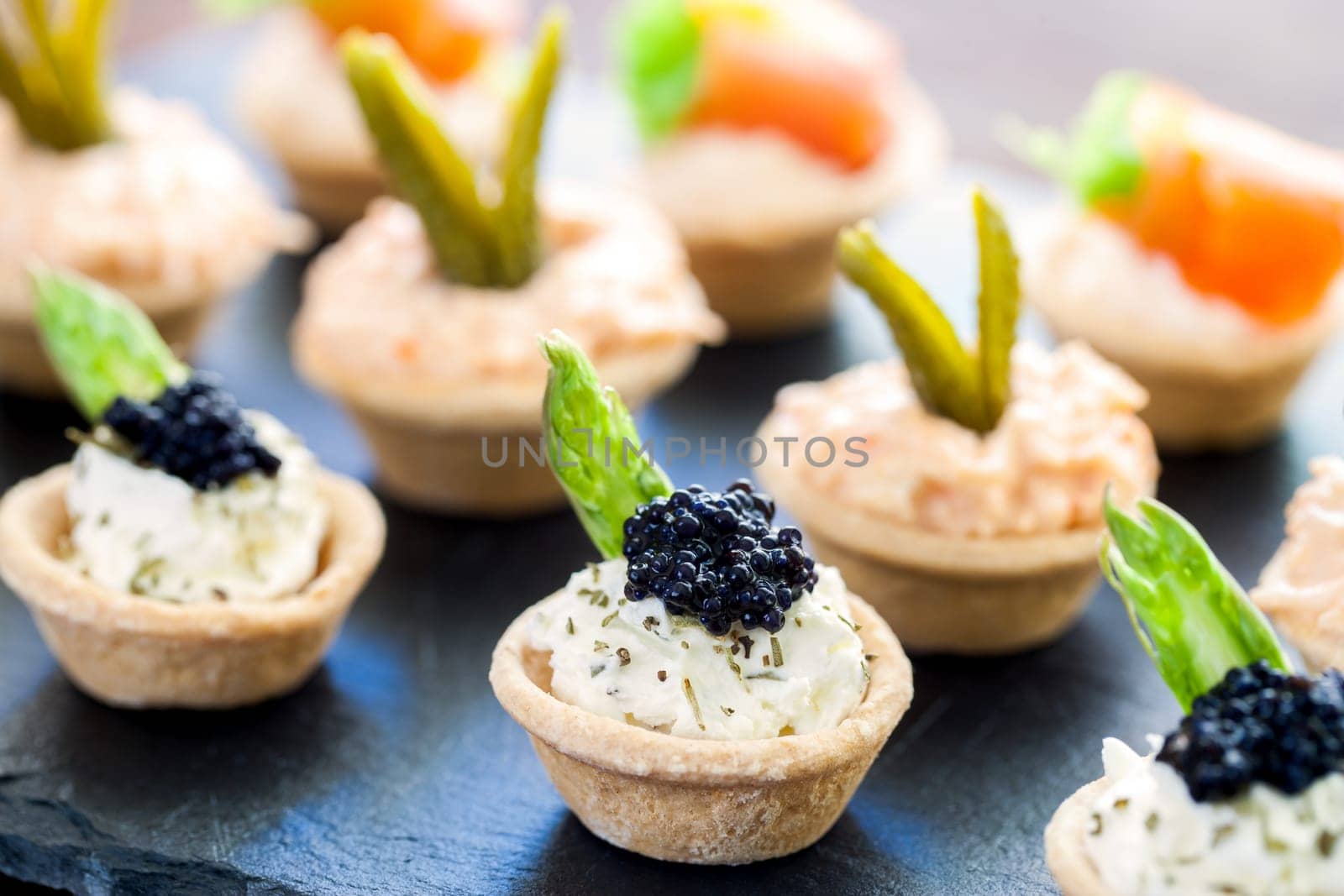 Macro close up of Multiple mini puff pastry tartlets with variety of savory fillings.