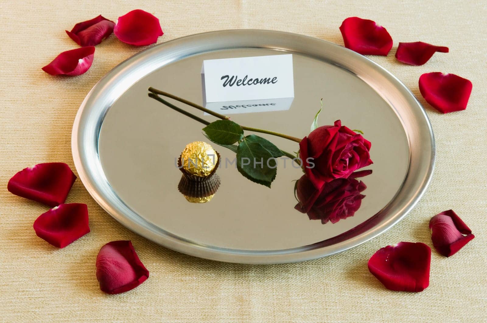 Close_up of a rose with sweet food and welcome note in a plate