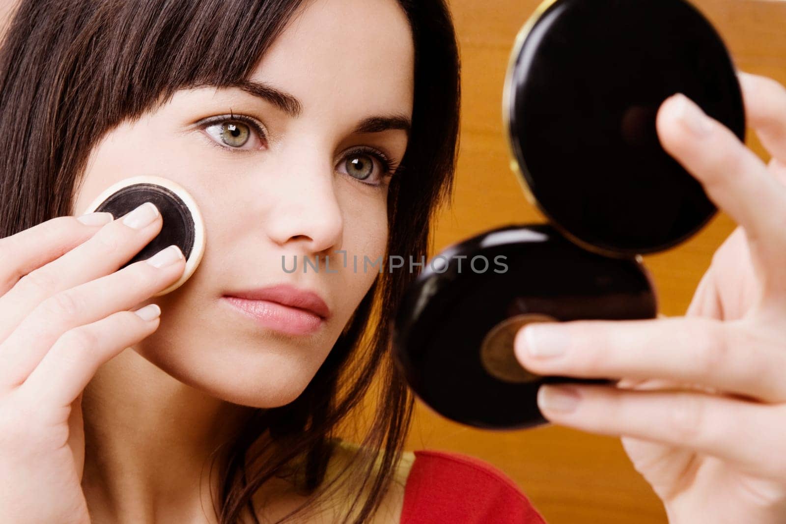 Young woman applying powder on her face