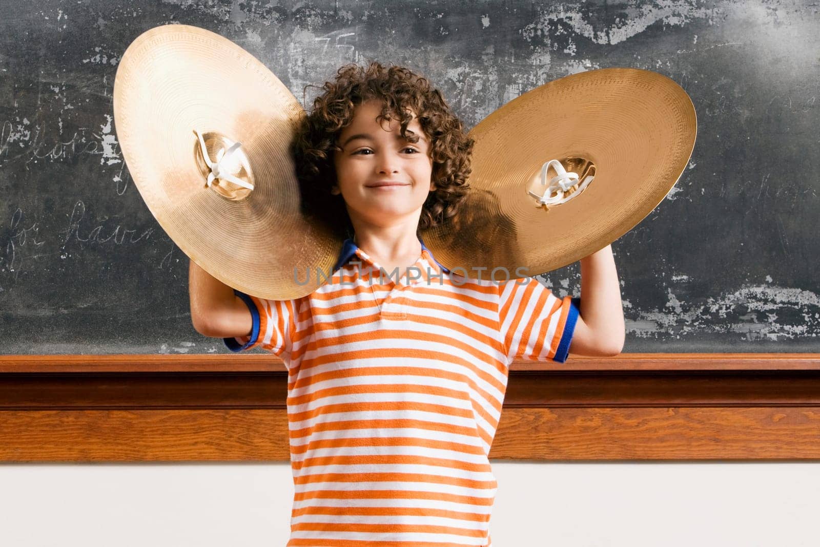 Schoolboy playing cymbals in a classroom