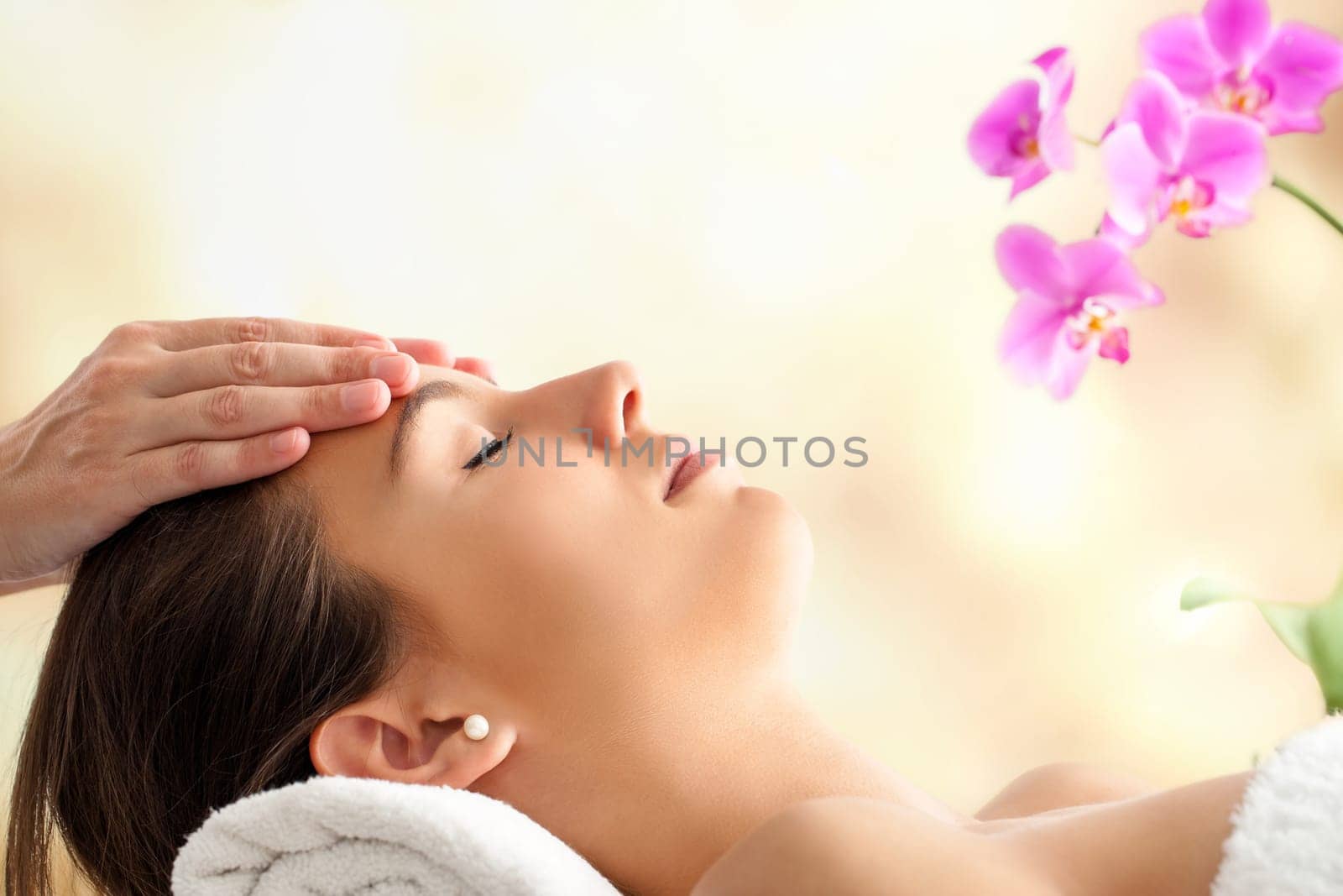 Close up  portrait of young Female Facial massage in spa. Therapist massaging woman’s head against bright colorful background.