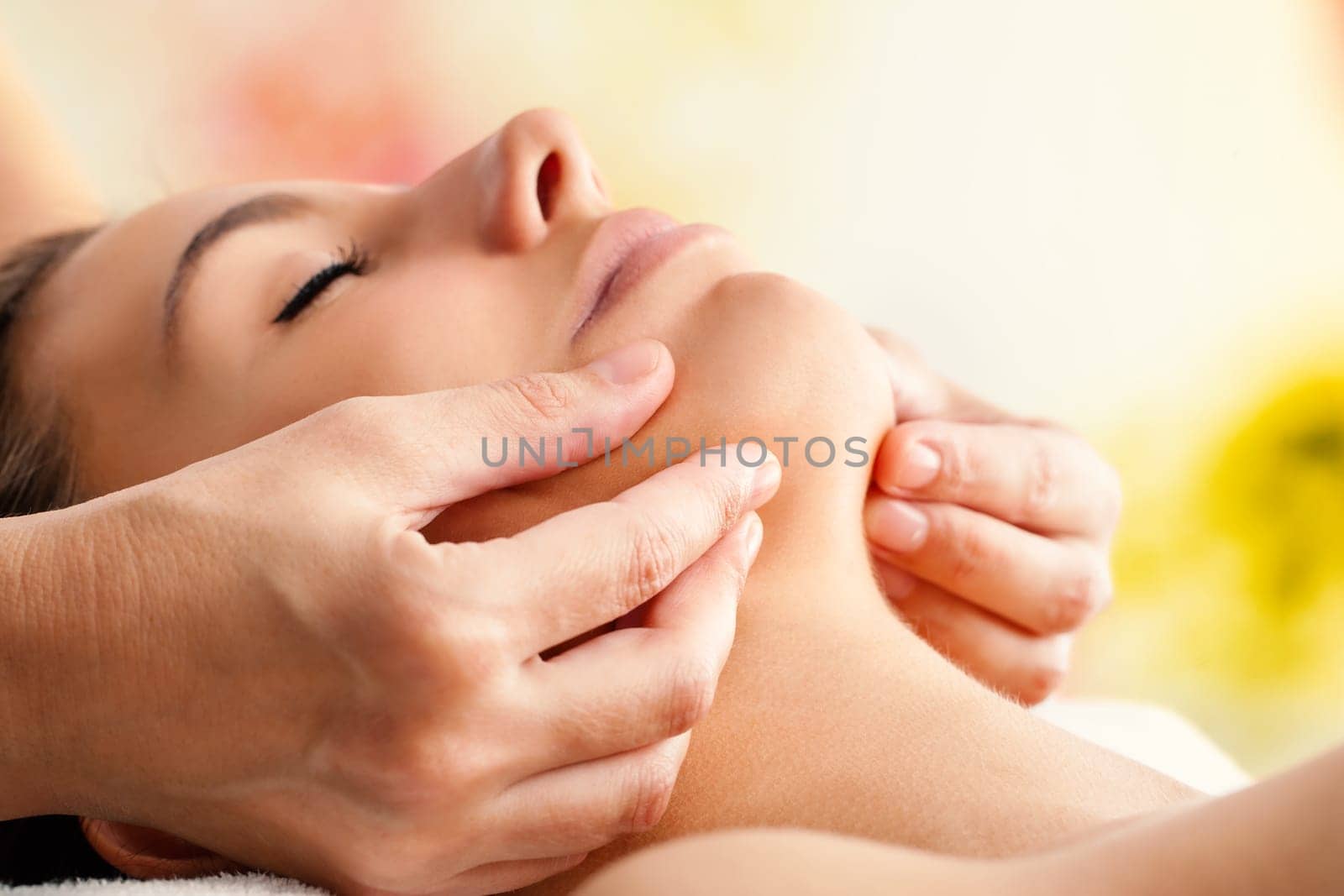 Macro close up of Hands massaging female chin. Therapist applying pressure with fingers on face.