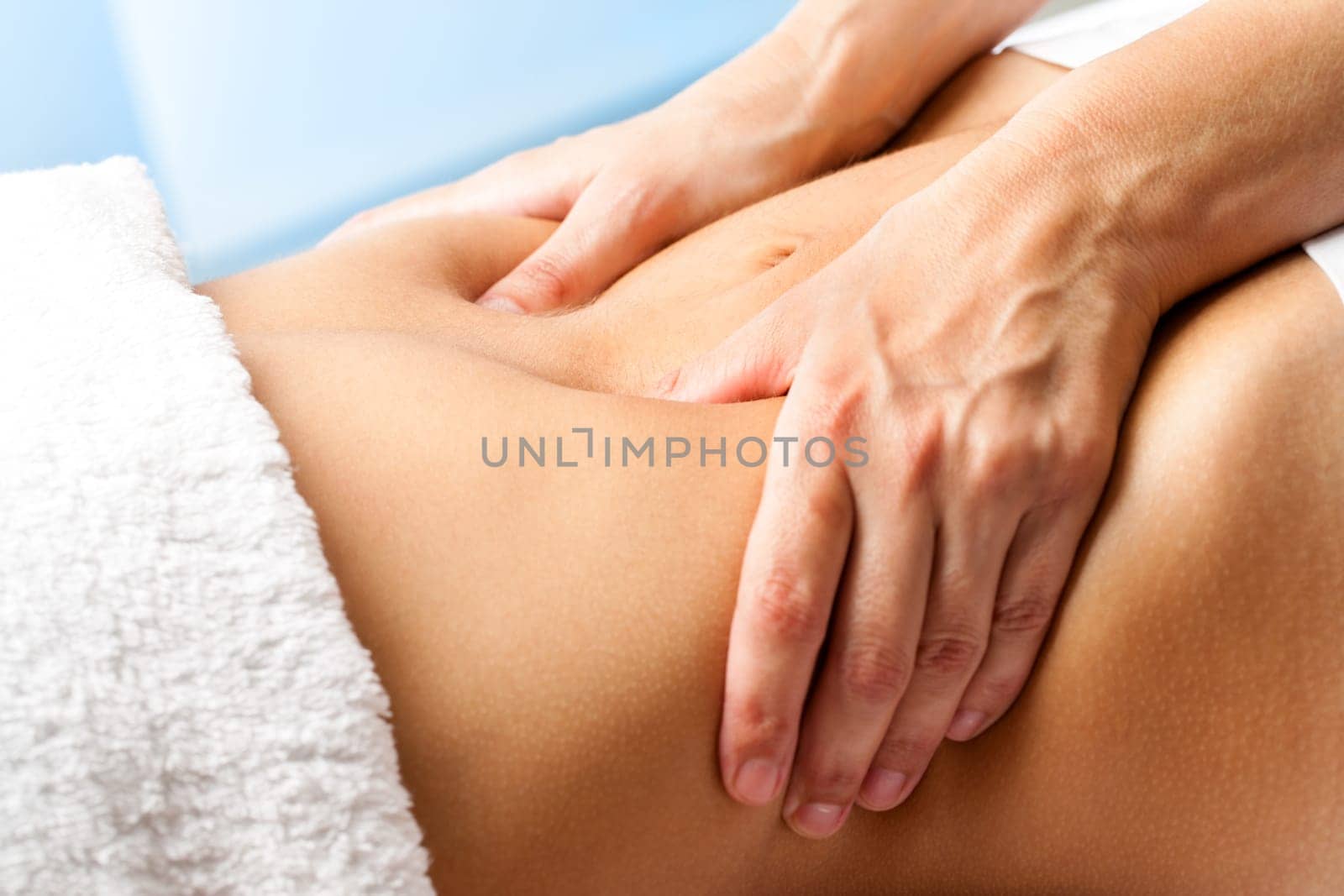 Macro close up of hands massaging female abdomen.Therapist applying pressure on belly.