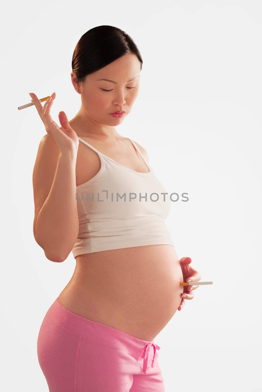 Pregnant woman holding a cigarette on her abdomen