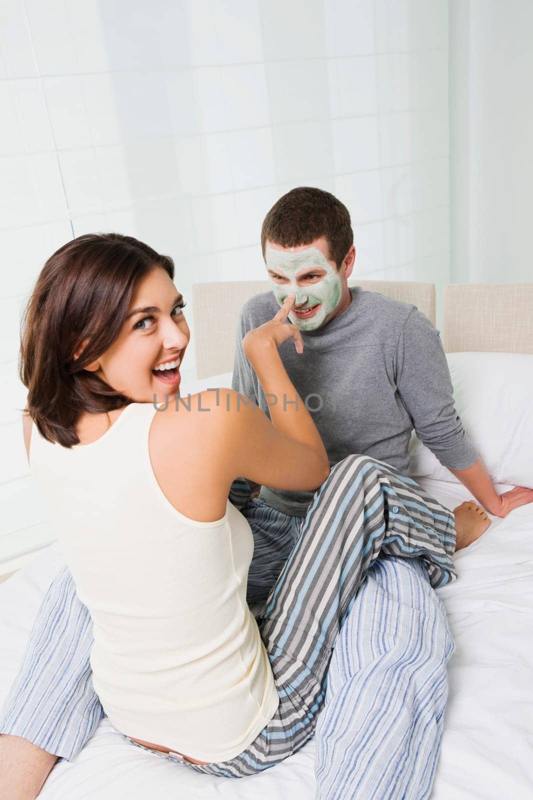 Portrait of a young woman applying facial mask on a young manŽs face