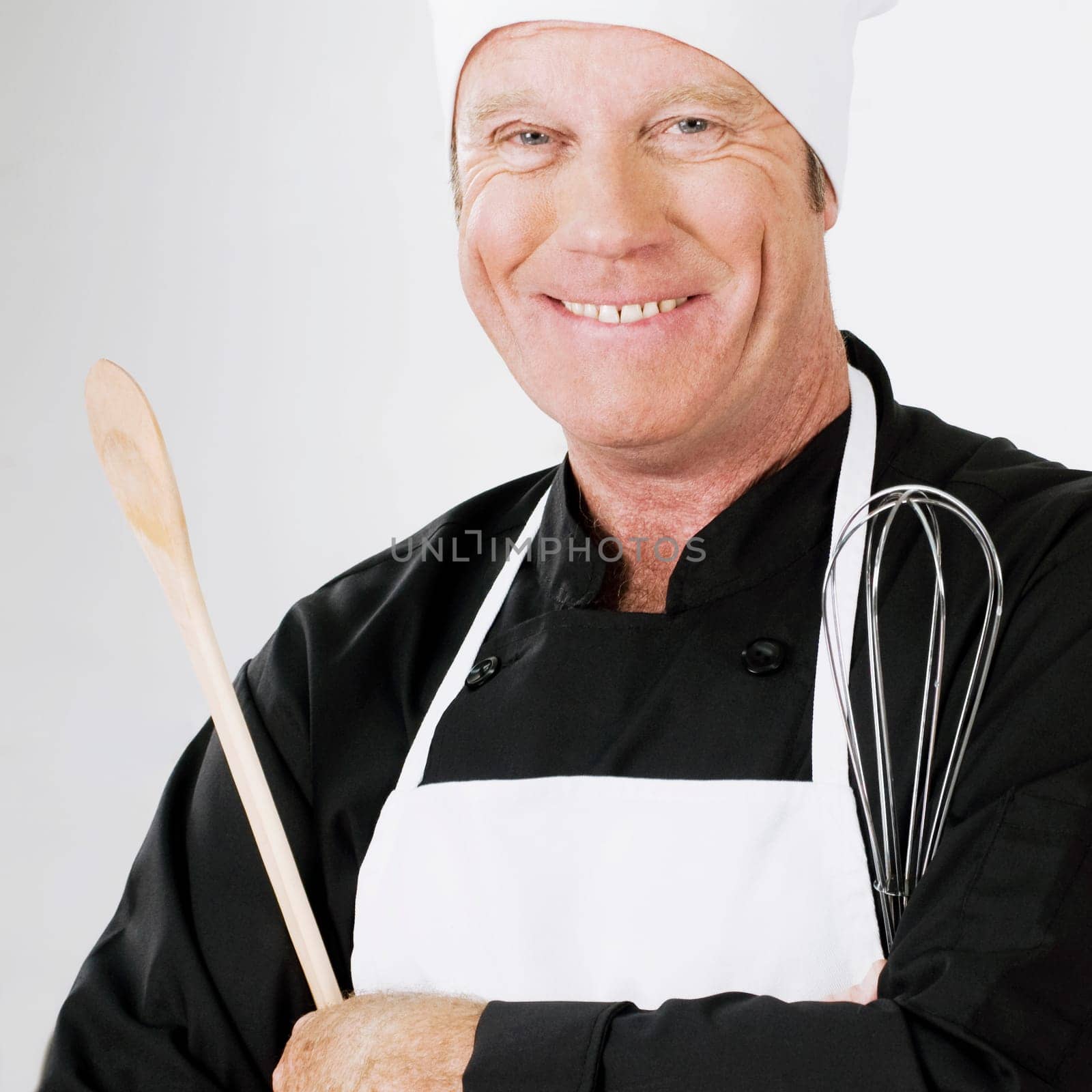 Chef holding a wooden spoon and a wire whisk