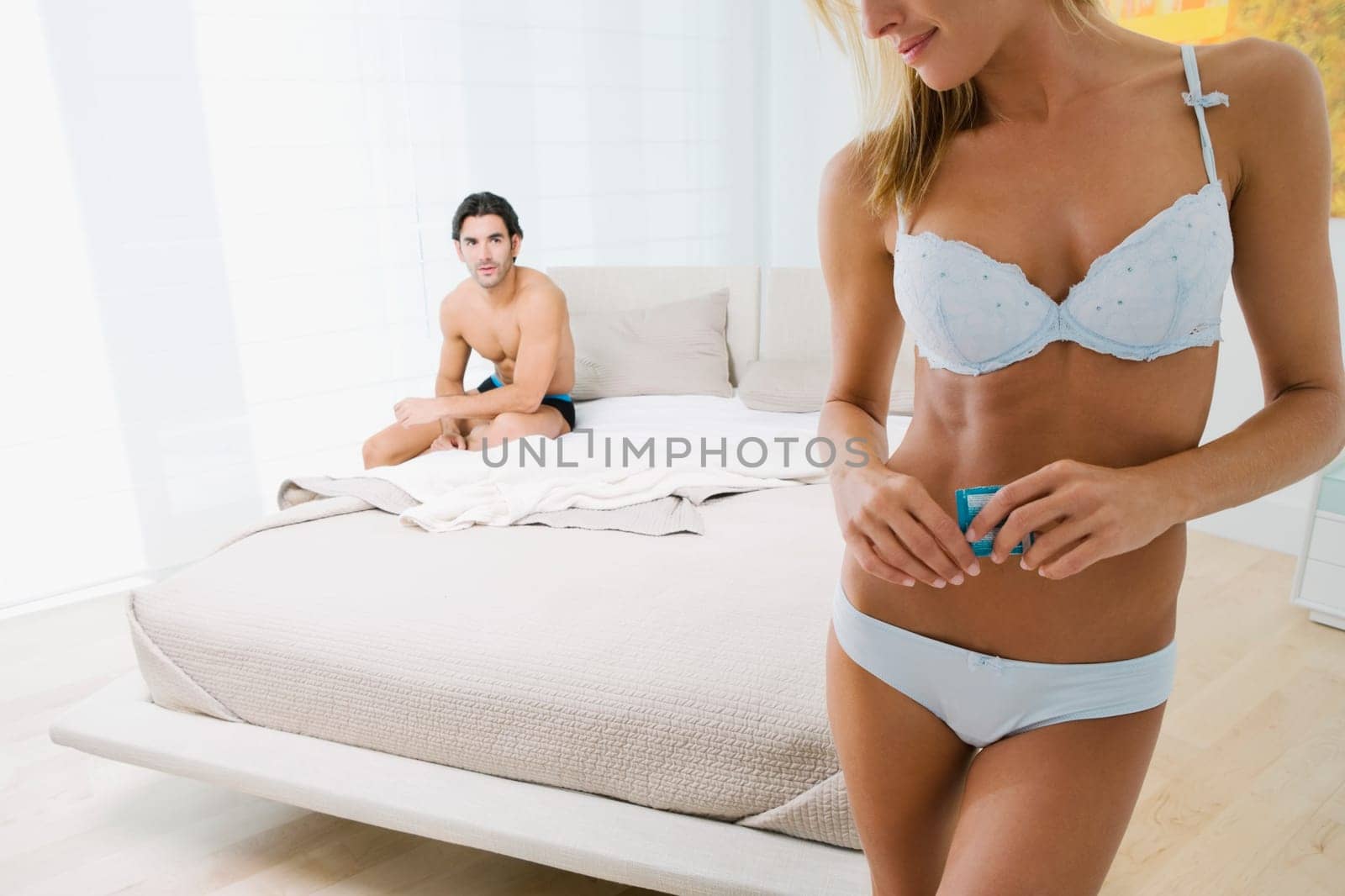 Mid adult woman holding a condom with a young man in the background