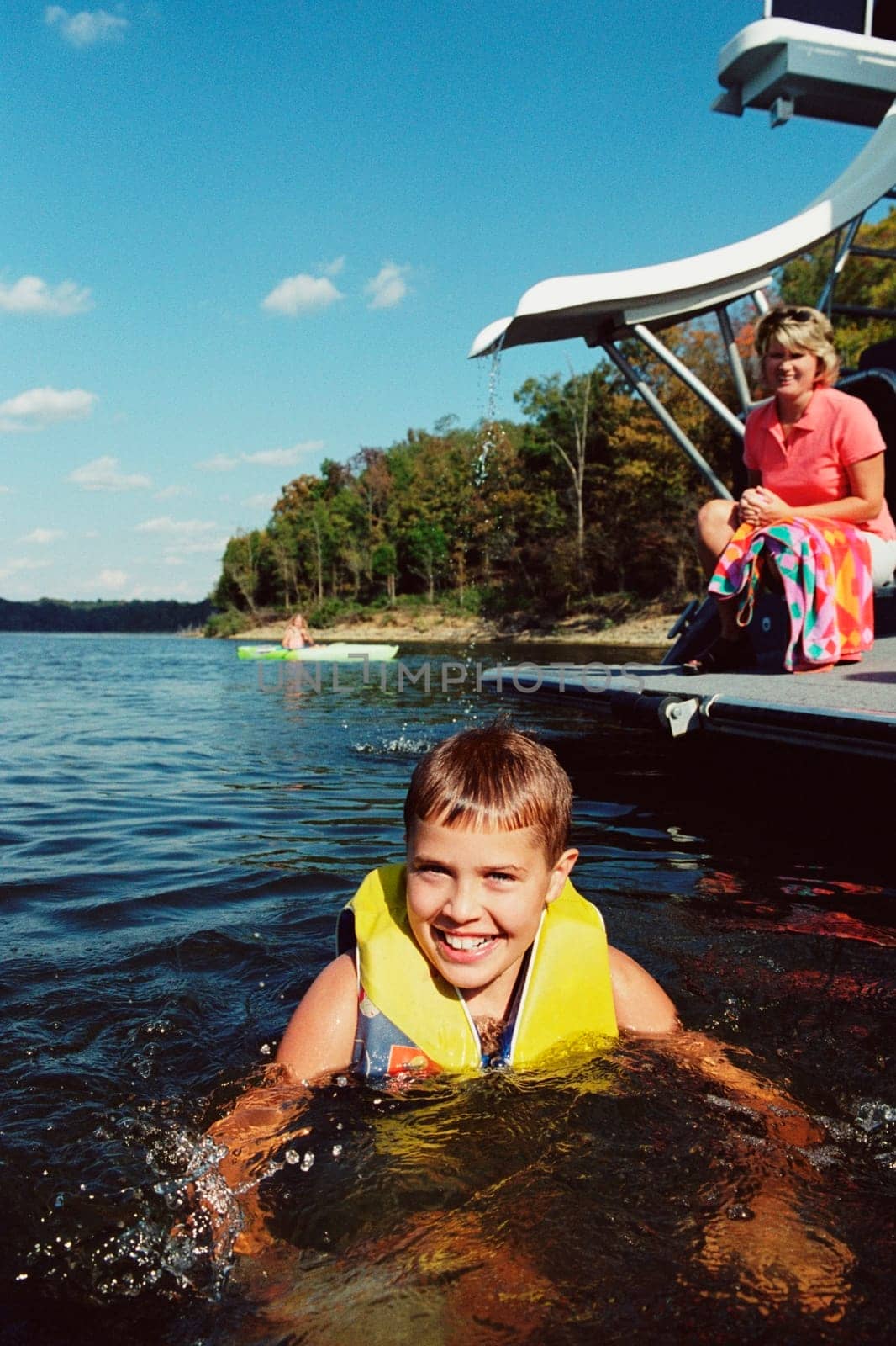 Portrait of a teenage boy swimming in a lake with her mother in the background, West Yellowstone, Montana, USA