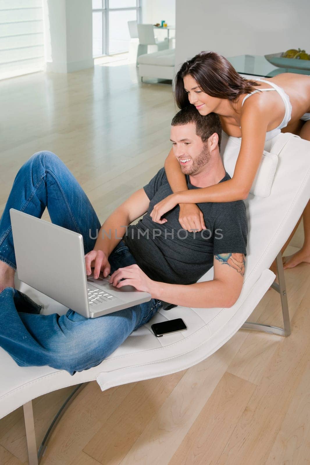 Young woman embracing a young man using a laptop and smiling