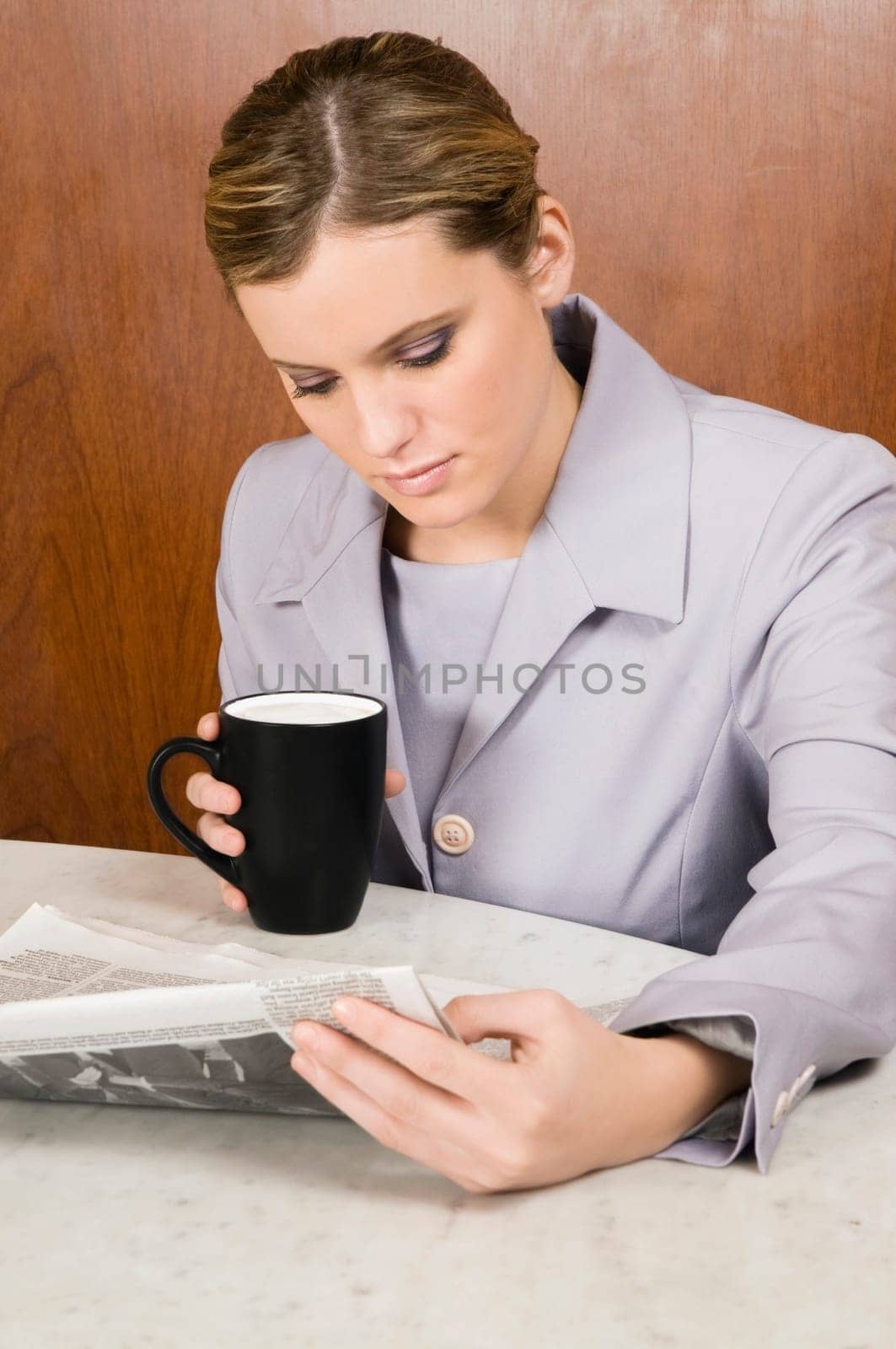 Businesswoman reading a newspaper and holding a coffee cup