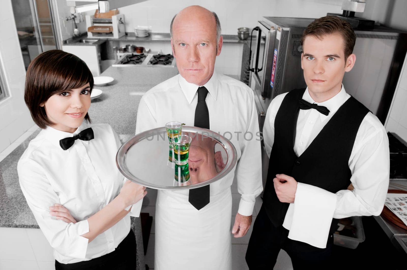 Two waiters and a waitress standing in the kitchen