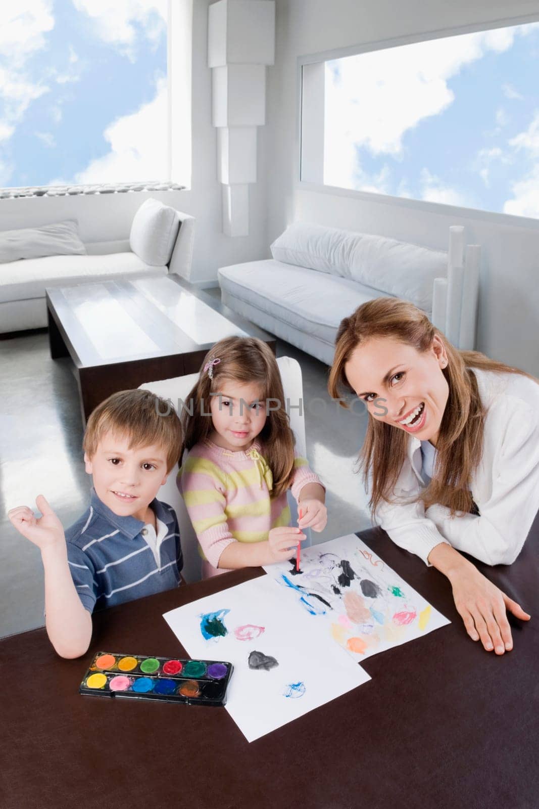 Portrait of a mid adult woman helping her children in painting