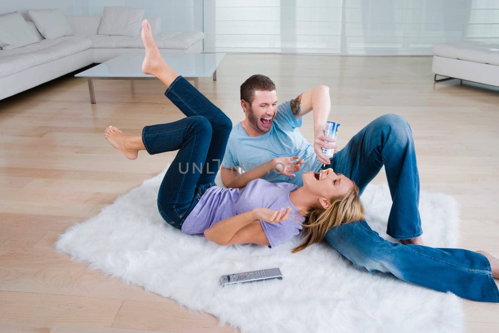 Young man feeding whipped cream from a bottle to a mid adult woman