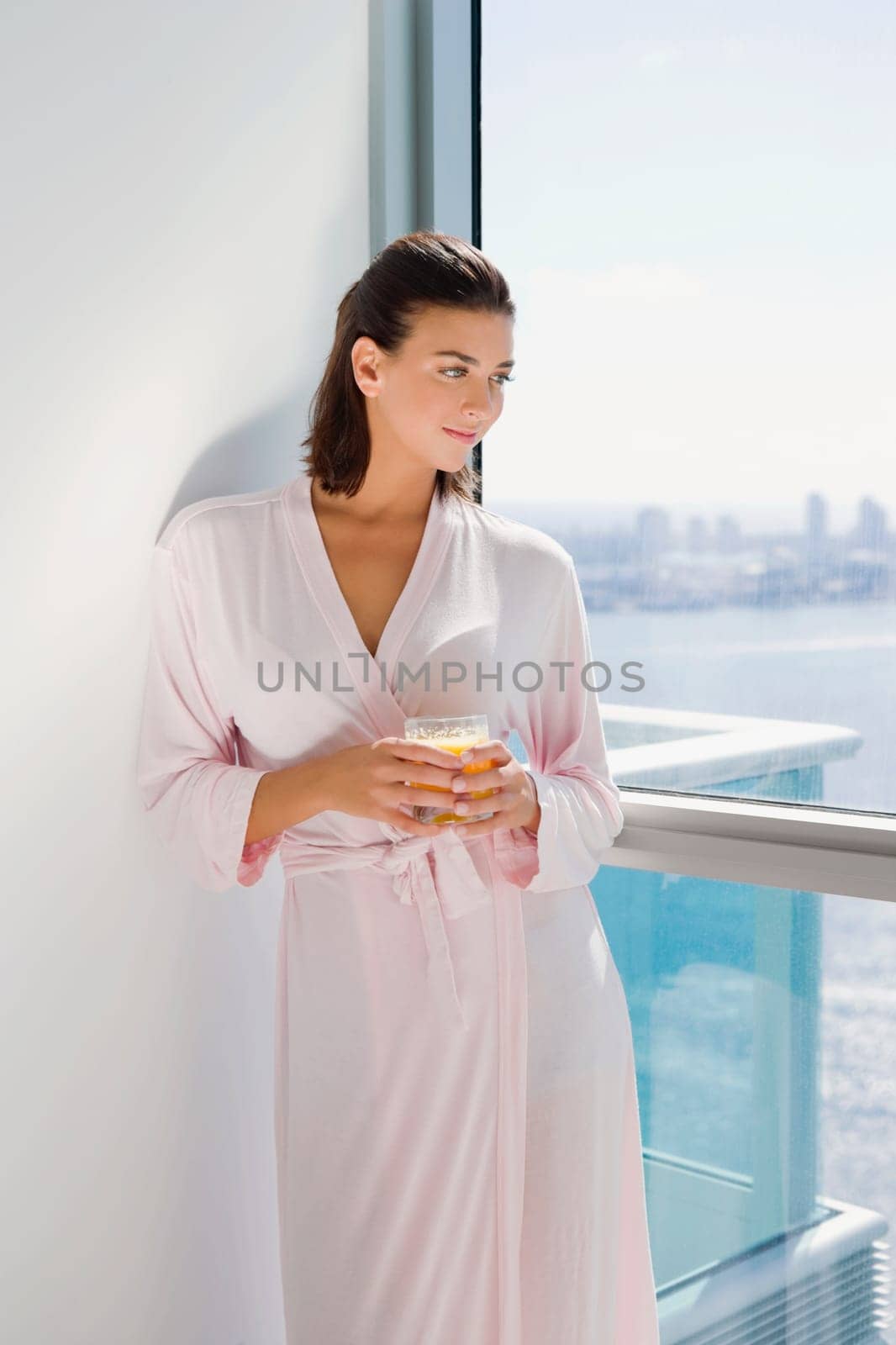 Young woman standing and holding a glass of juice