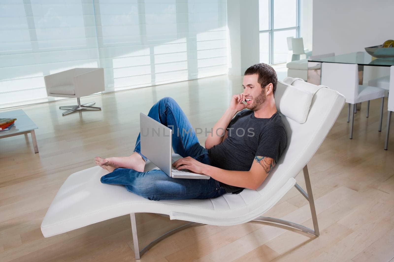 Side profile of a young man using a laptop and talking on a mobile phone