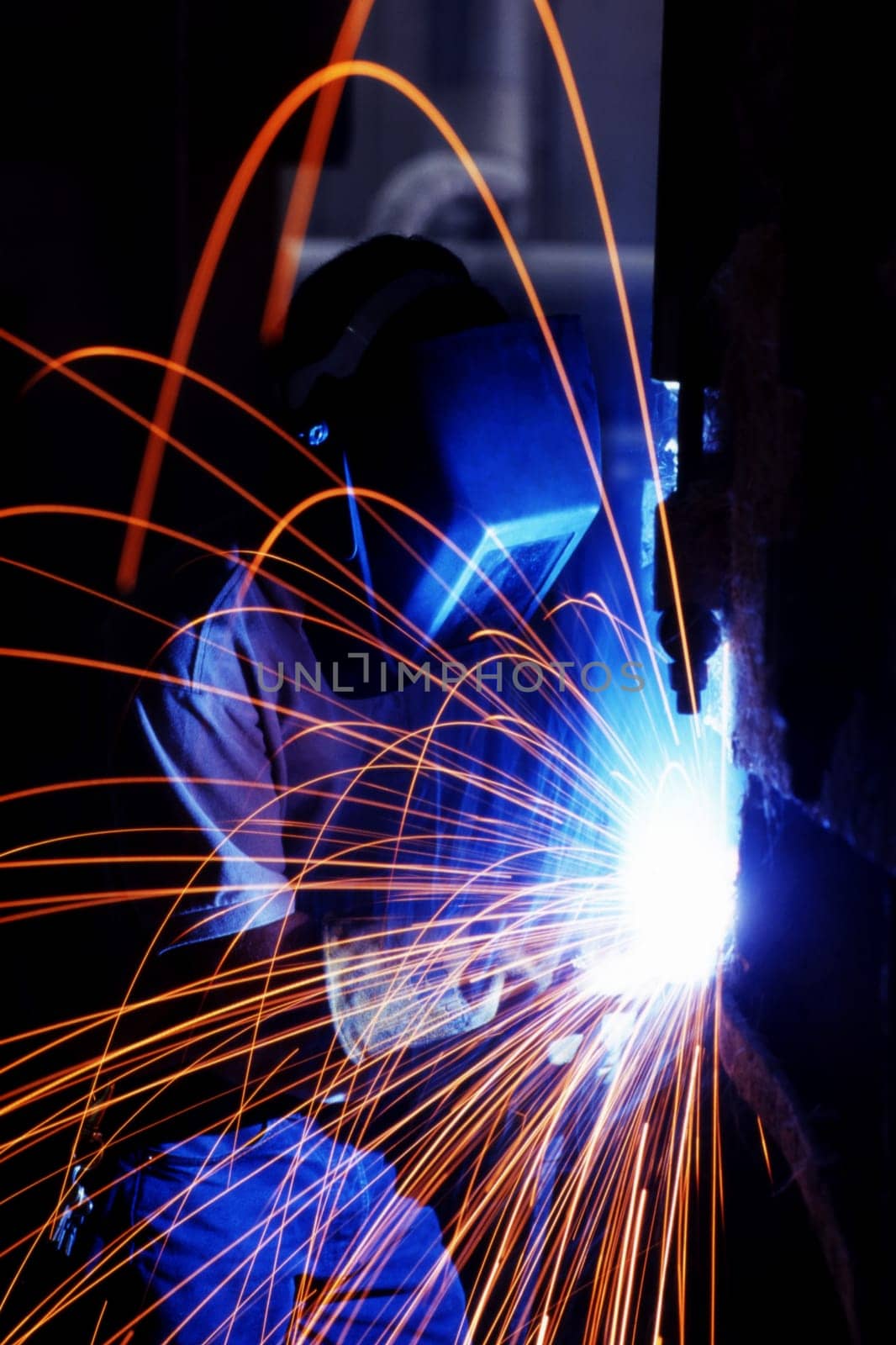 Welder working on a piece of metal with sparks flying